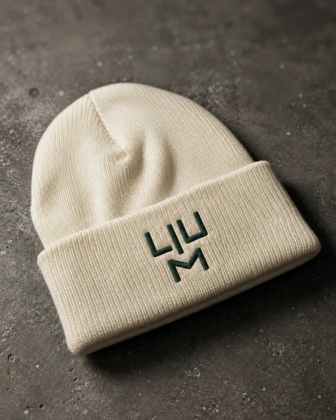 A cream LIUM beanie with a green embroidered logo on dark stone
